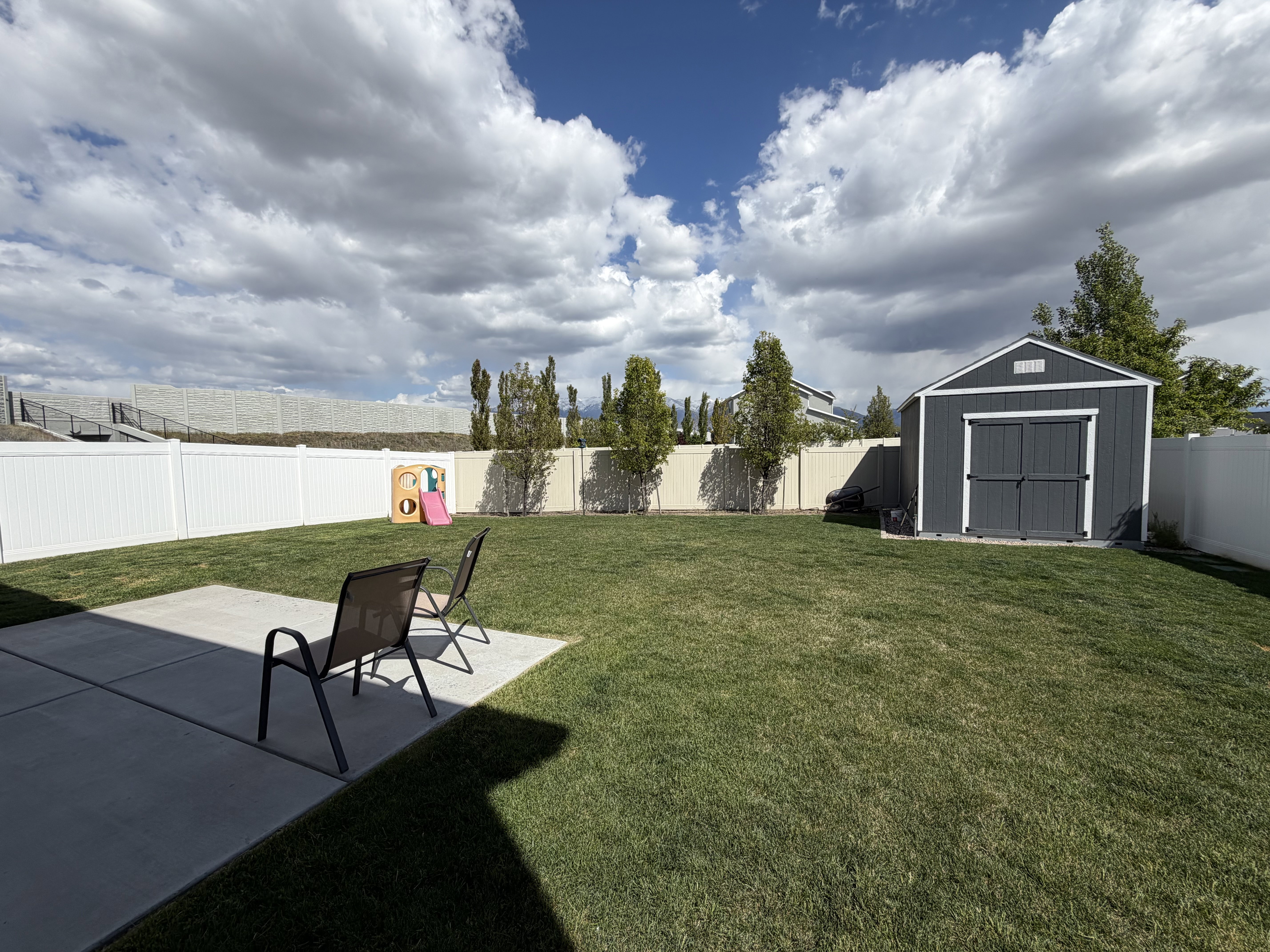 Fenced backyard with a shed and a patio
