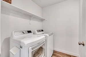 Laundry room with washing machine and dryer and light wood-style flooring