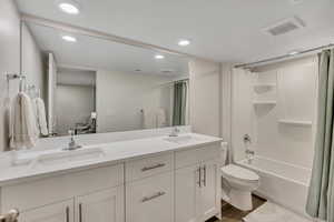 Bathroom with recessed lighting, double vanity, shower / tub combo, and light wood-style flooring