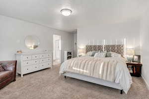 Bedroom with light carpet and a textured ceiling