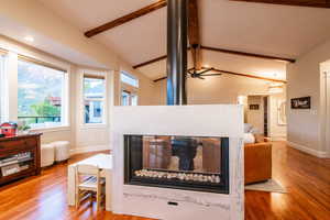 Striking double-sided gas fireplace with quartzite surround and custom metal flue serves as a centerpiece between the main living areas