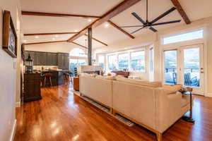 Light-filled living room featuring vaulted ceilings, exposed wood beams, and a striking double-sided fireplace, all framed by breathtaking mountain views