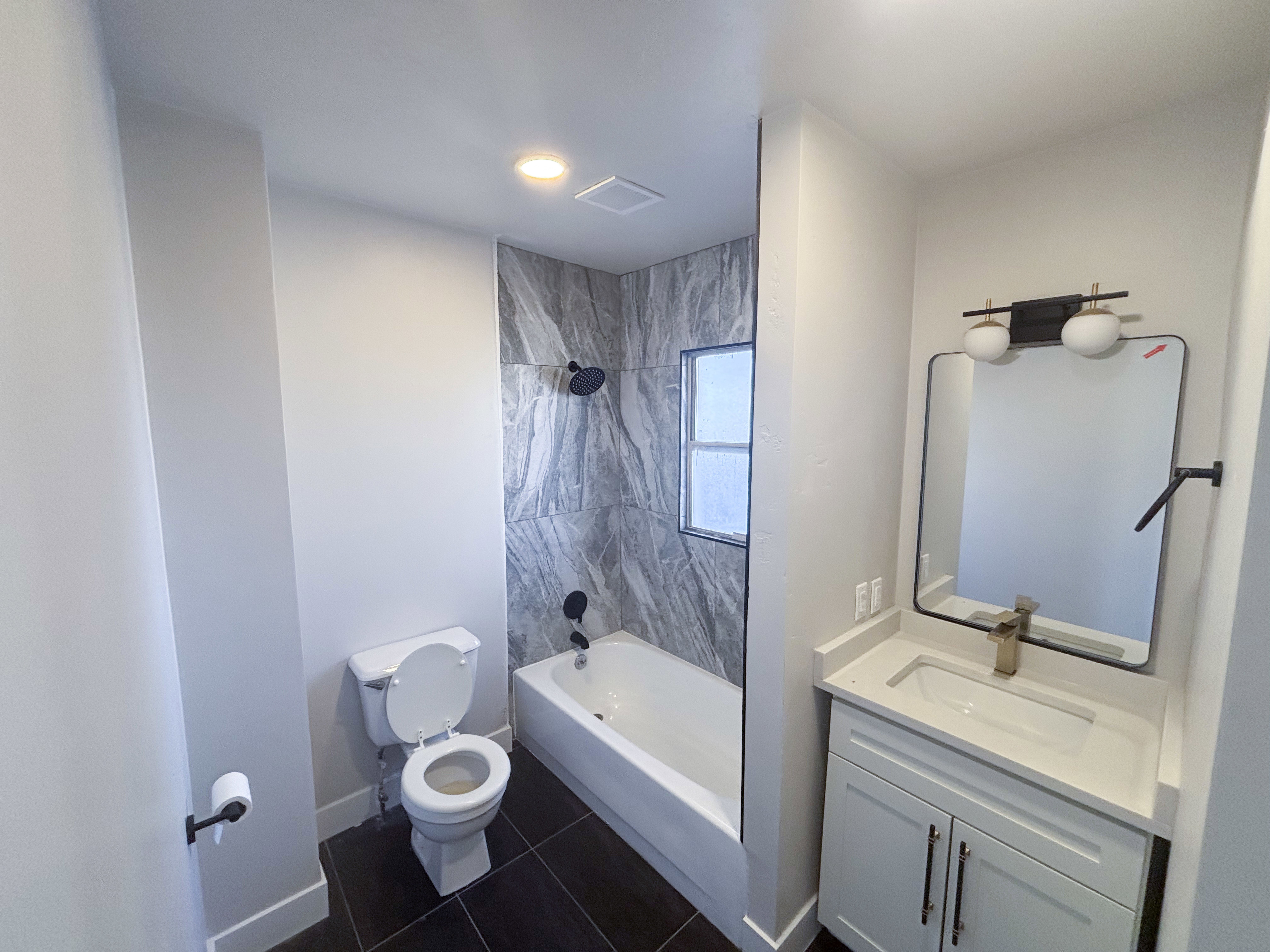 Bathroom featuring vanity, dark tile patterned flooring, and bathing tub / shower combination