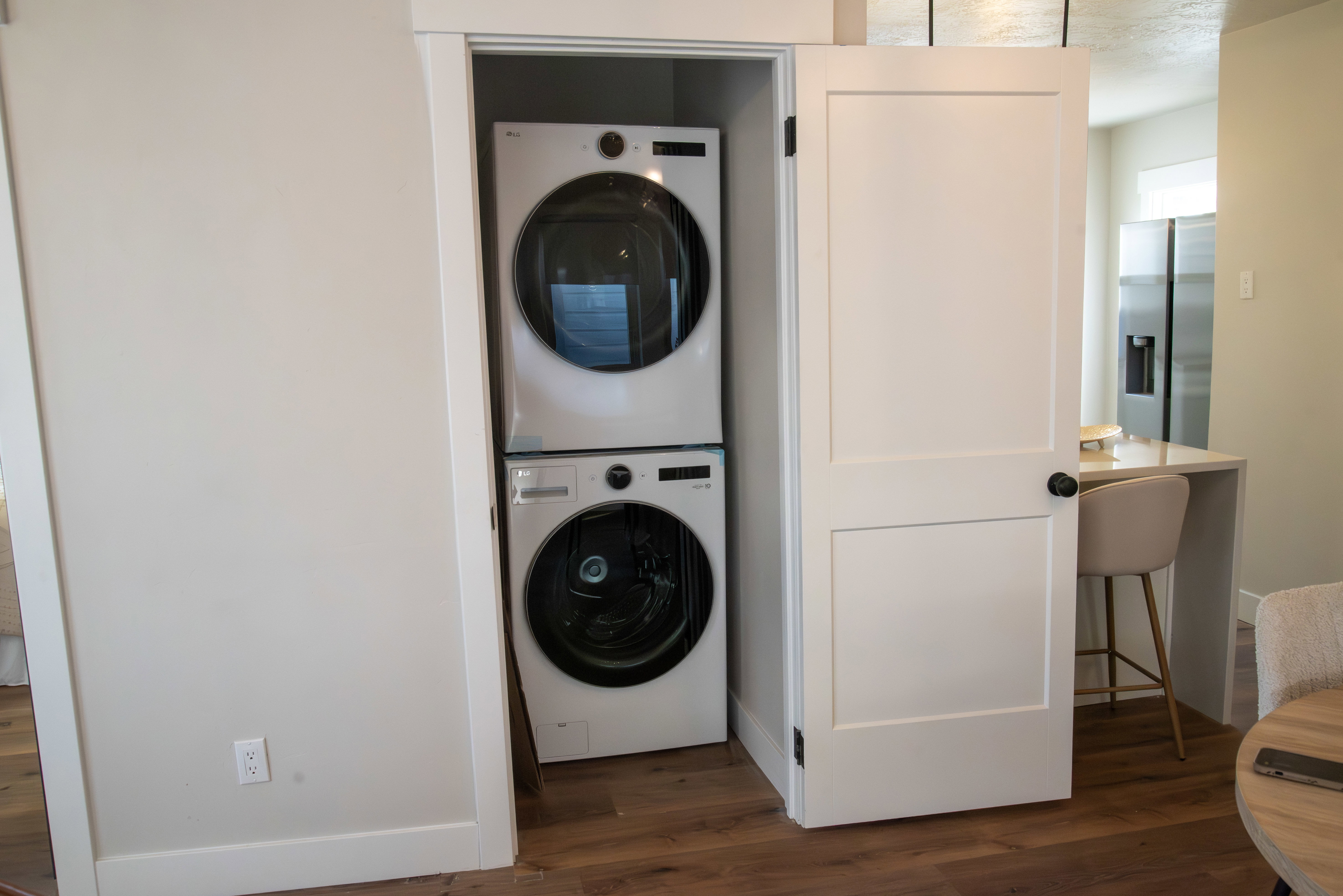 Laundry area featuring dark wood-style flooring and stacked washing machine and dryer