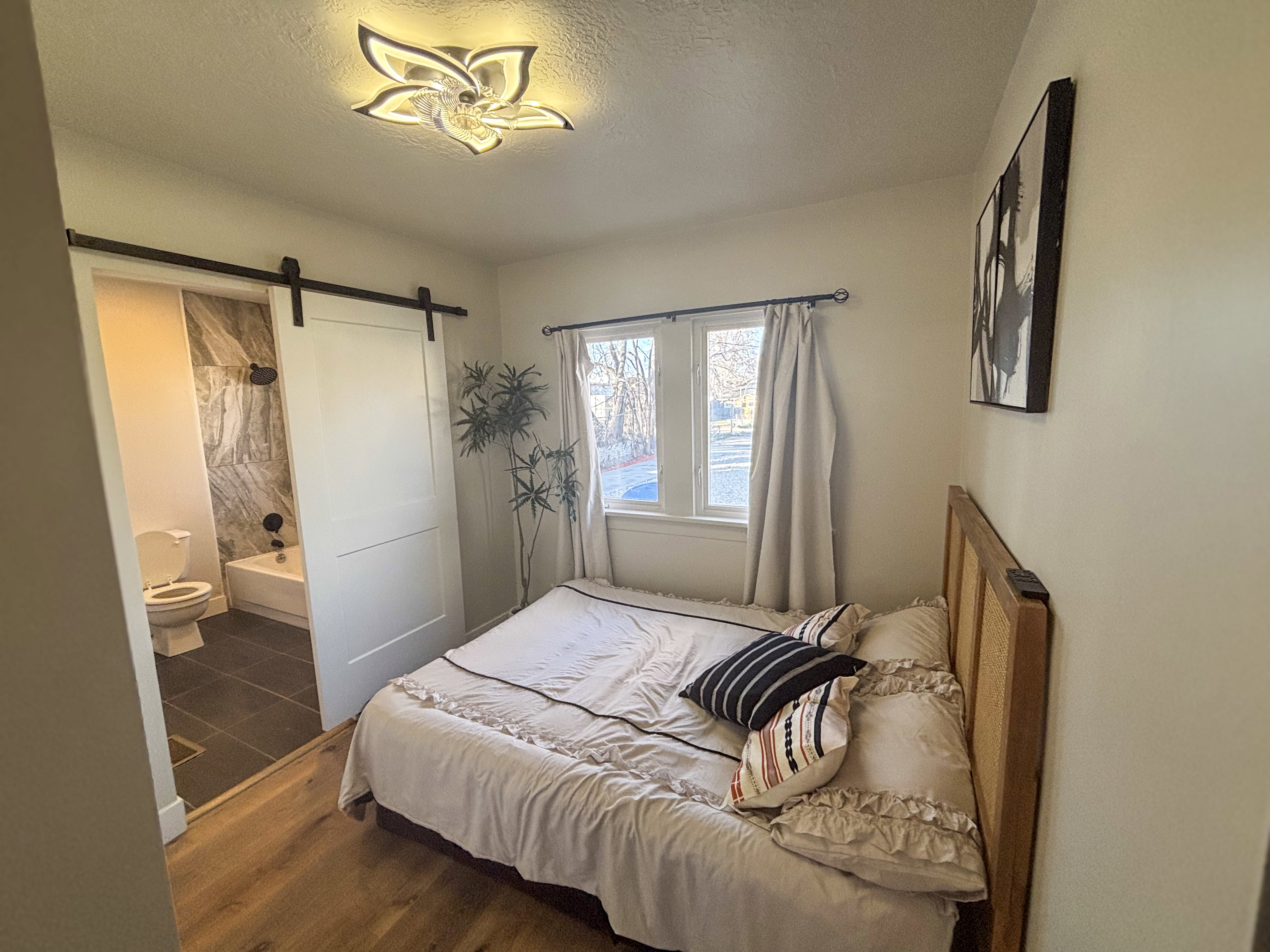 Bedroom with a barn door, a textured ceiling, ensuite bathroom, and dark wood finished floors