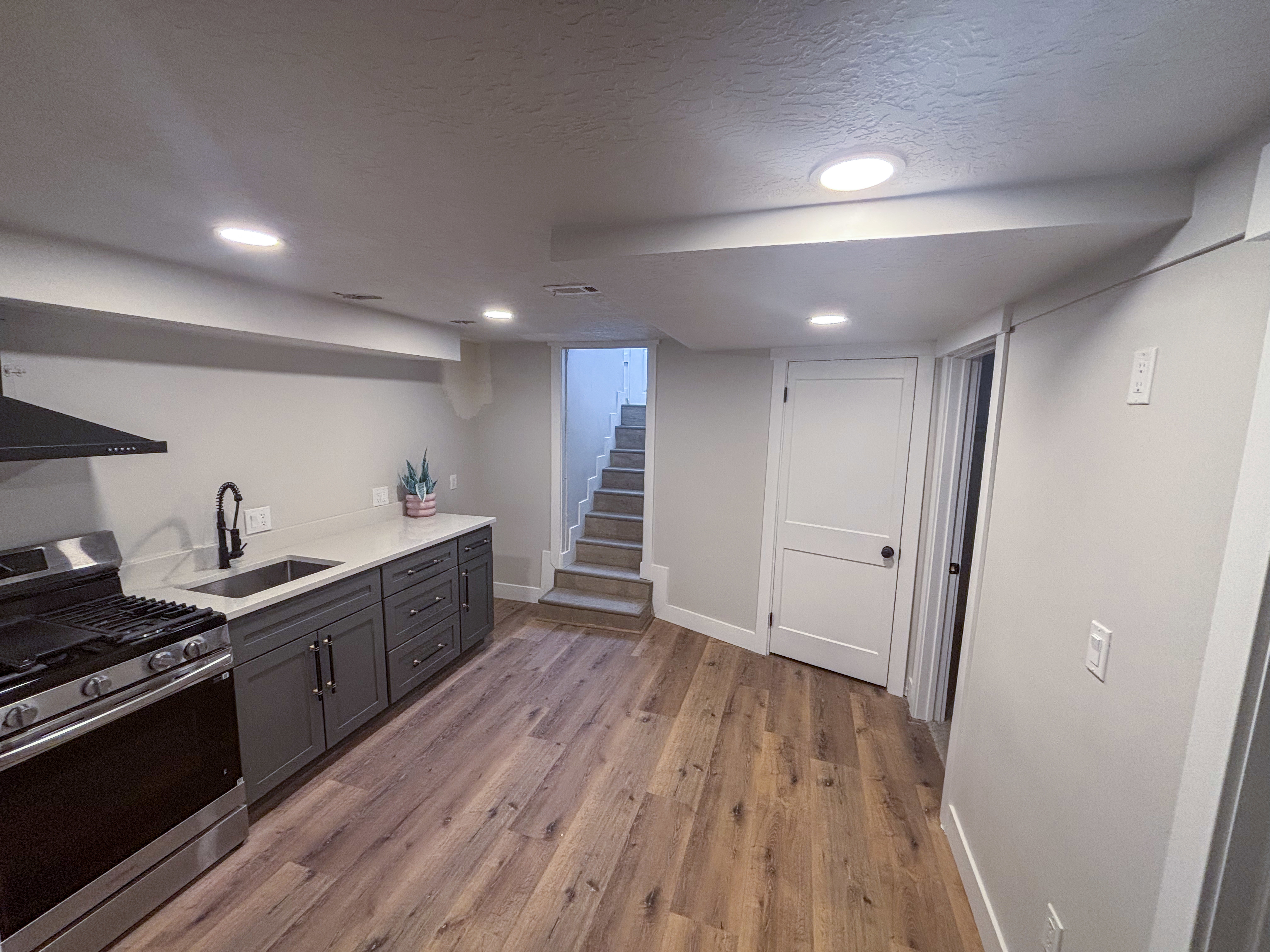 Kitchen featuring stainless steel range with gas stovetop, a textured ceiling, recessed lighting, light stone counters, and light wood finished floors