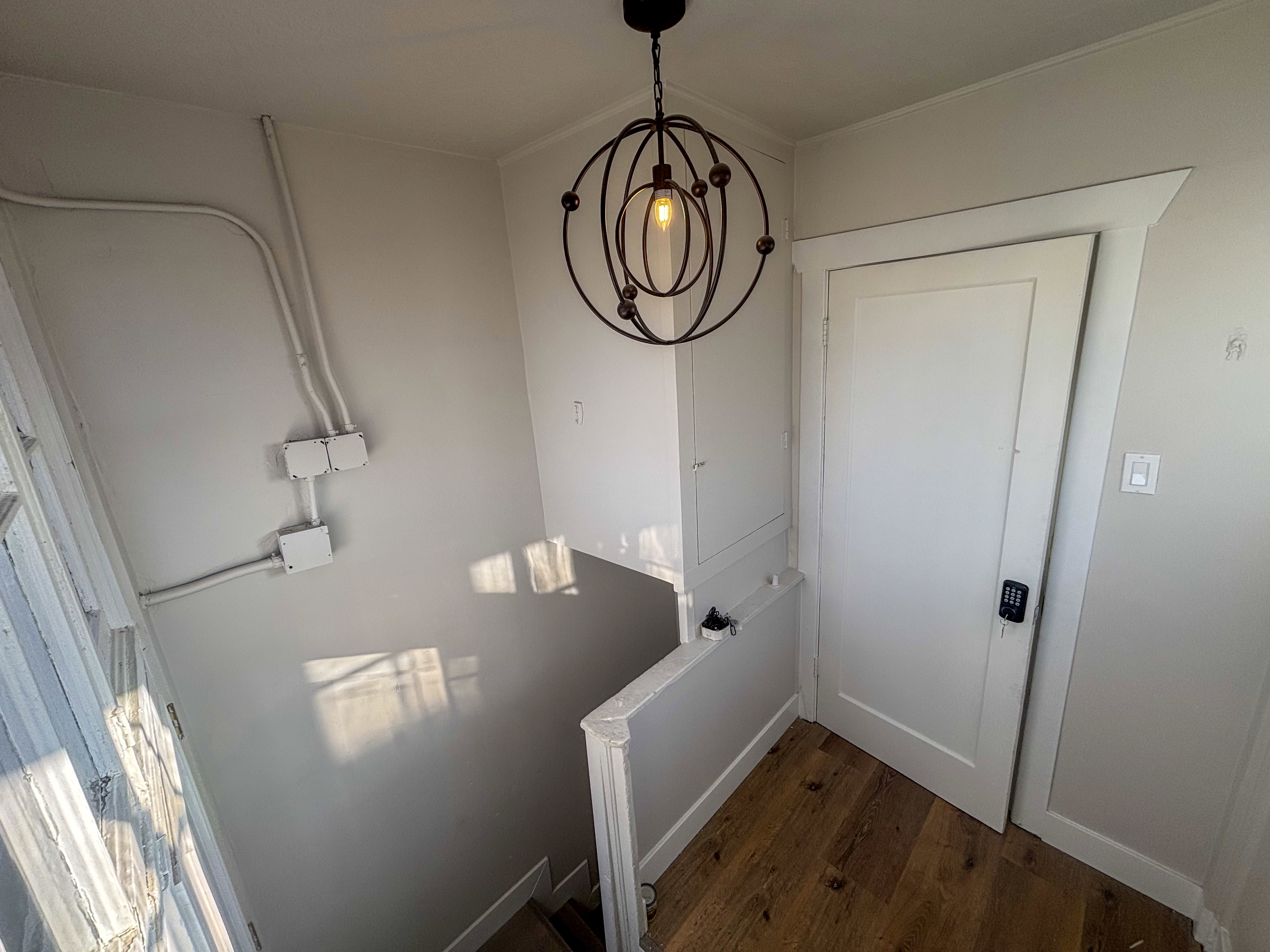 Laundry area featuring dark wood finished floors and a chandelier