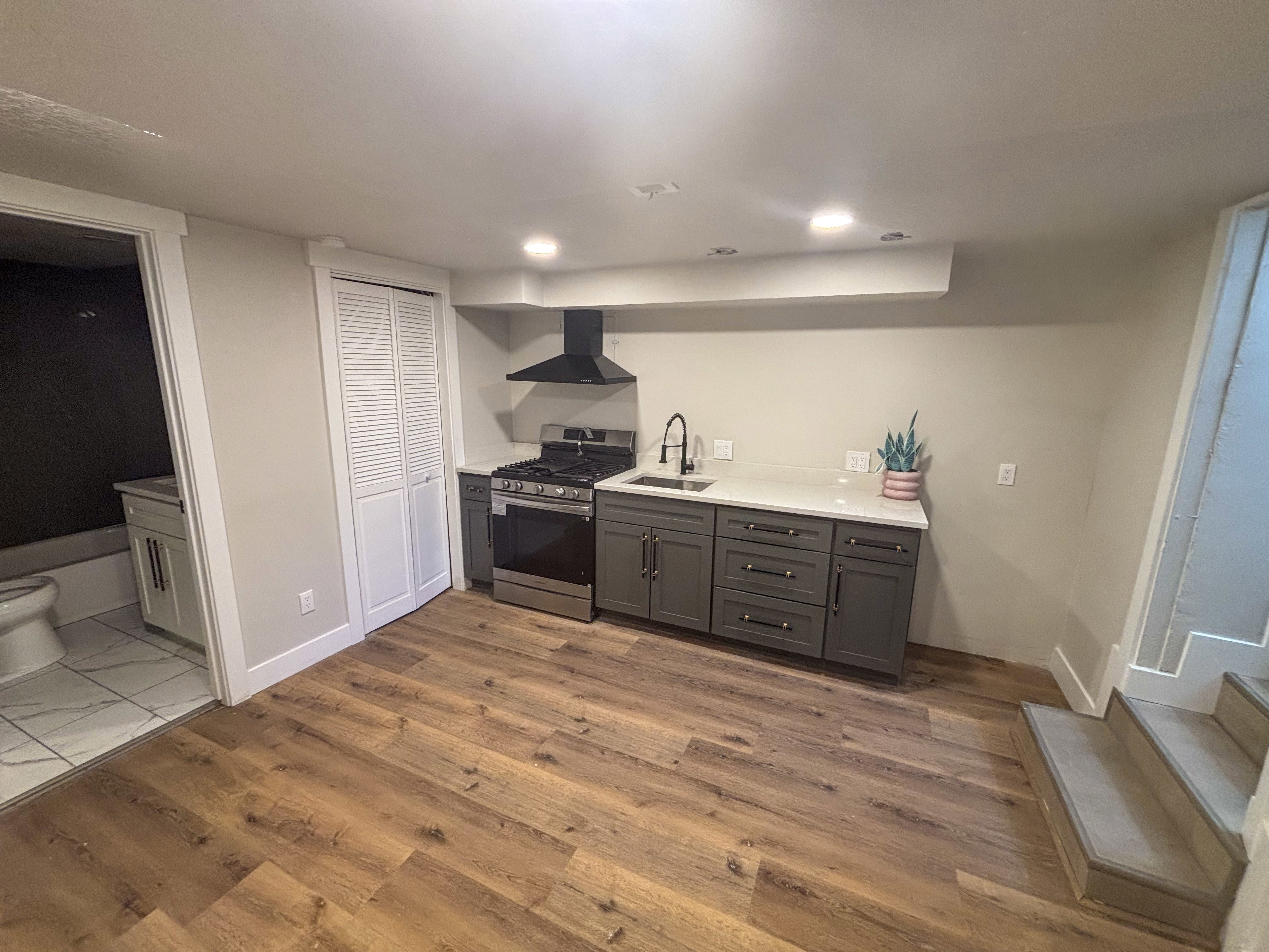 Kitchen featuring gas stove, gray cabinetry, and wood finished floors