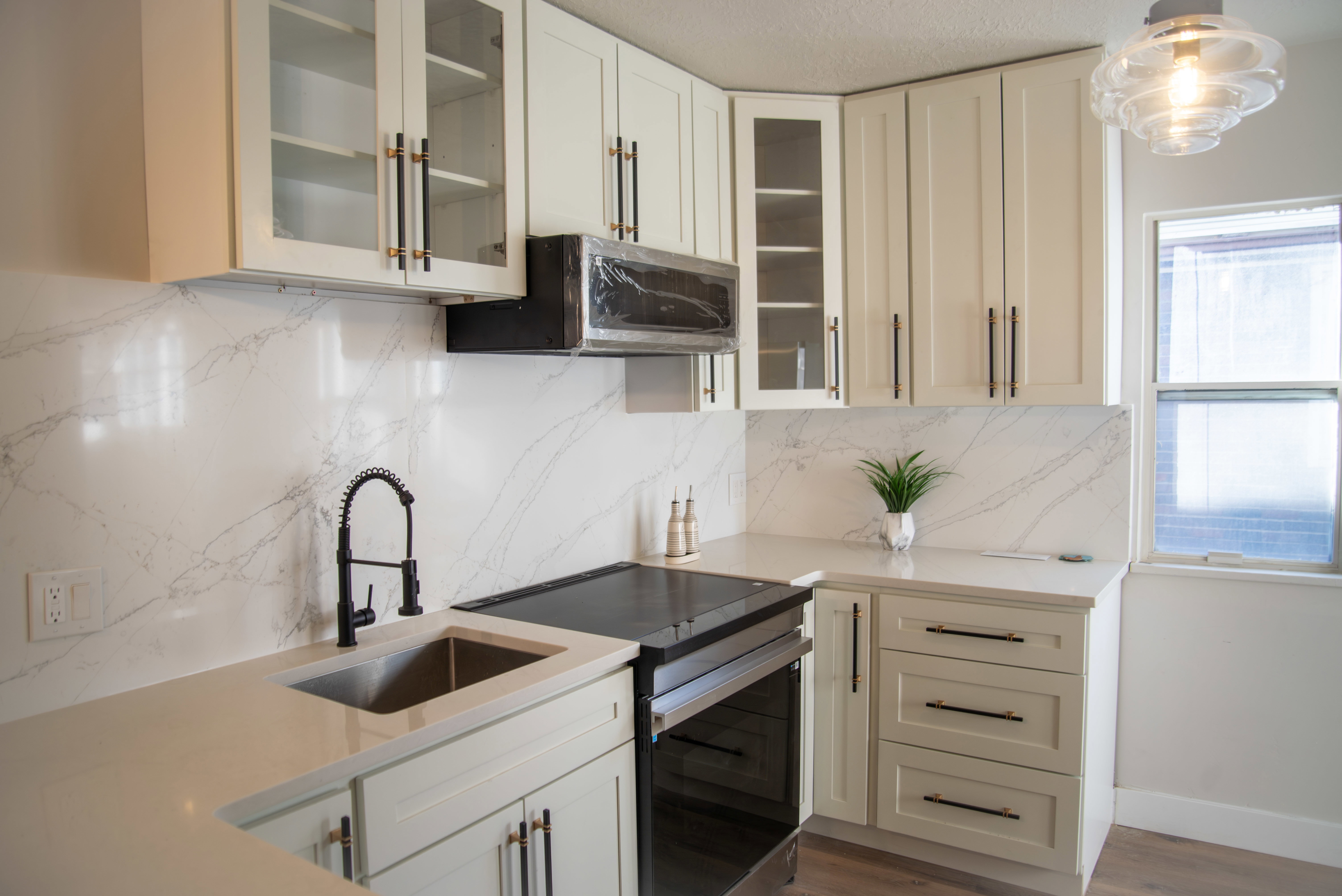 Kitchen with range with electric cooktop, light stone counters, tasteful backsplash, glass insert cabinets, and stainless steel microwave
