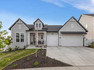 Modern farmhouse style home featuring board and batten siding, a porch, driveway, a garage, and a standing seam roof