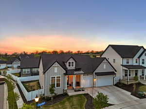 Modern inspired farmhouse with a standing seam roof, board and batten siding, covered porch, concrete driveway, and an attached garage