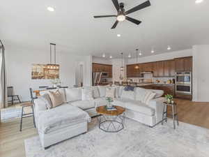 Living room featuring light wood finished floors, a ceiling fan, and recessed lighting
