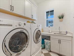Laundry area with cabinet space, independent washer and dryer, and light floors