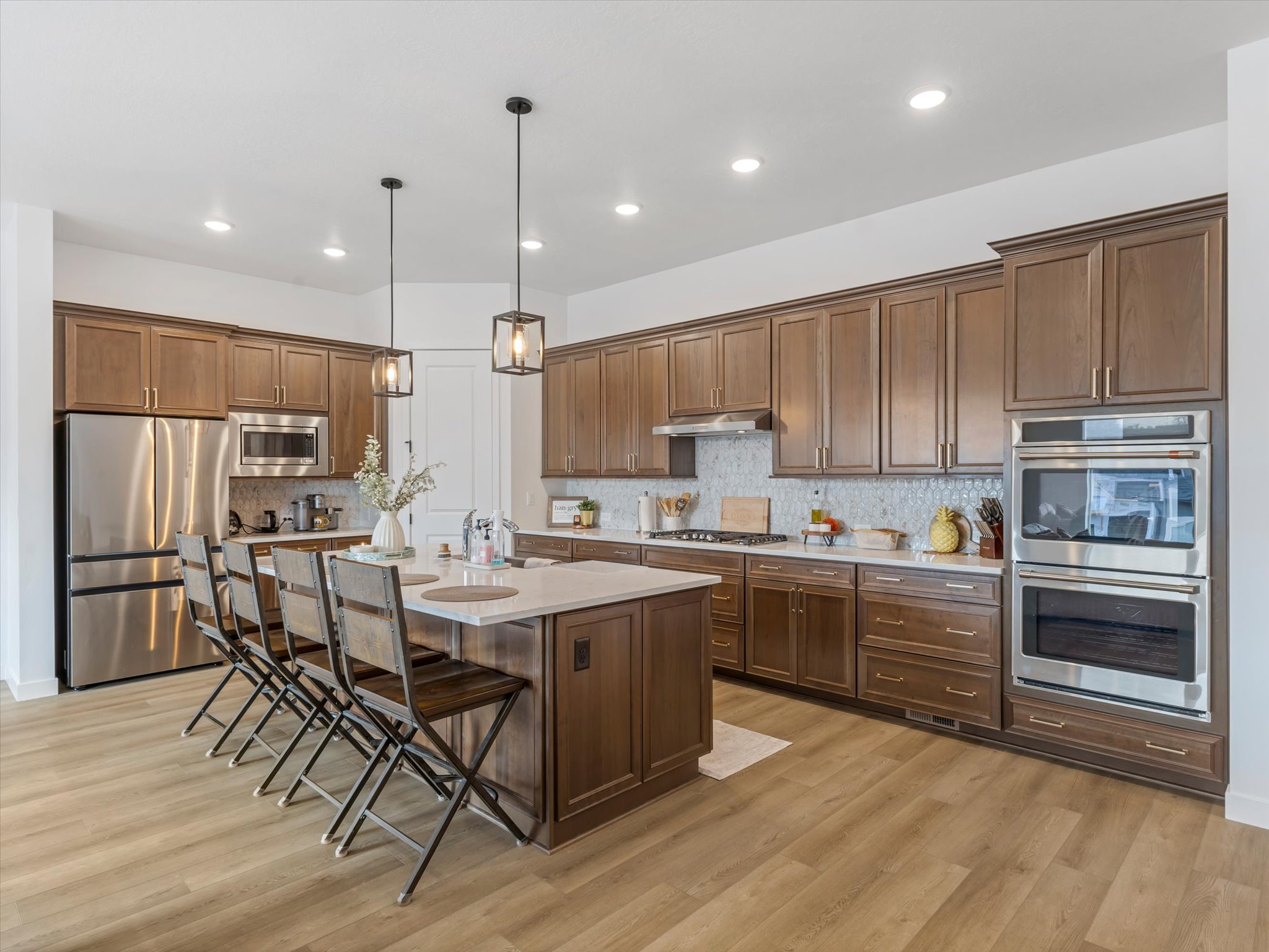 Kitchen with a breakfast bar, stainless steel appliances, pendant lighting, a center island with sink, and light wood-type flooring
