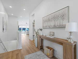 Corridor with an upstairs landing, light wood-style floors, and recessed lighting