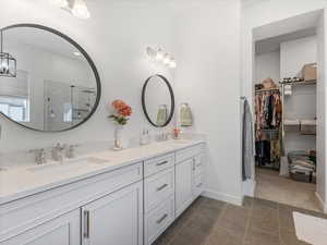 Full bath featuring double vanity, a stall shower, and a spacious closet