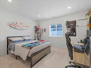 Bedroom with light colored carpet, an office area, and recessed lighting