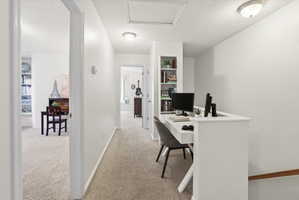 Office space with a textured ceiling, light colored carpet, and built in shelves