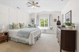 Bedroom with light carpet, lofted ceiling, a ceiling fan, and a decorative wall