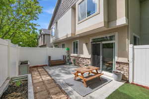 Rear view of house featuring a fenced backyard, stone siding, and stucco siding