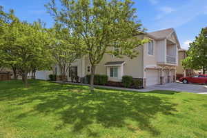 View of front of property with a garage, a front yard, stucco siding, stone siding, and a shingled roof