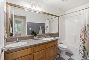 Bathroom featuring double vanity and shower / bath combination with curtain