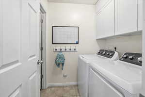 Laundry room with cabinet space, washer and clothes dryer, and light tile patterned floors