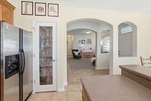 Kitchen featuring stainless steel refrigerator with ice dispenser, arched walkways, and light tile patterned floors