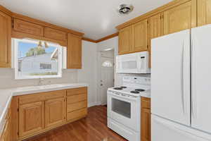Kitchen with white appliances, crown molding, dark wood-style flooring, tile counters, and tasteful backsplash