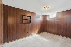 Basement with light carpet and a textured ceiling