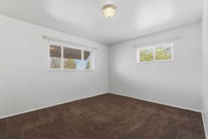 Spare room with dark carpet and baseboards