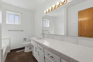 Bathroom with vanity, a garden tub, and dark carpet