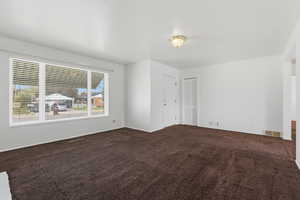 Spare room featuring dark colored carpet and baseboards