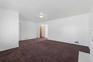 Empty room featuring dark colored carpet and baseboards