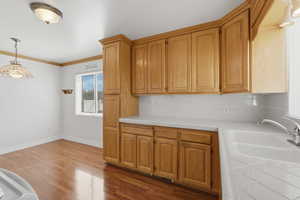 Kitchen featuring tile counters, tasteful backsplash, ornamental molding, pendant lighting, and dark wood-style flooring