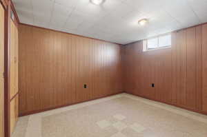 Unfurnished room featuring light flooring and wood walls
