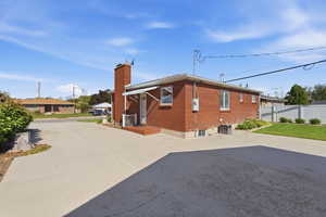 View of property exterior with a chimney and brick siding