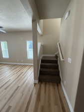 Staircase with a textured ceiling and wood finished floors