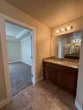 Bathroom with a textured ceiling, vanity, and dark carpet