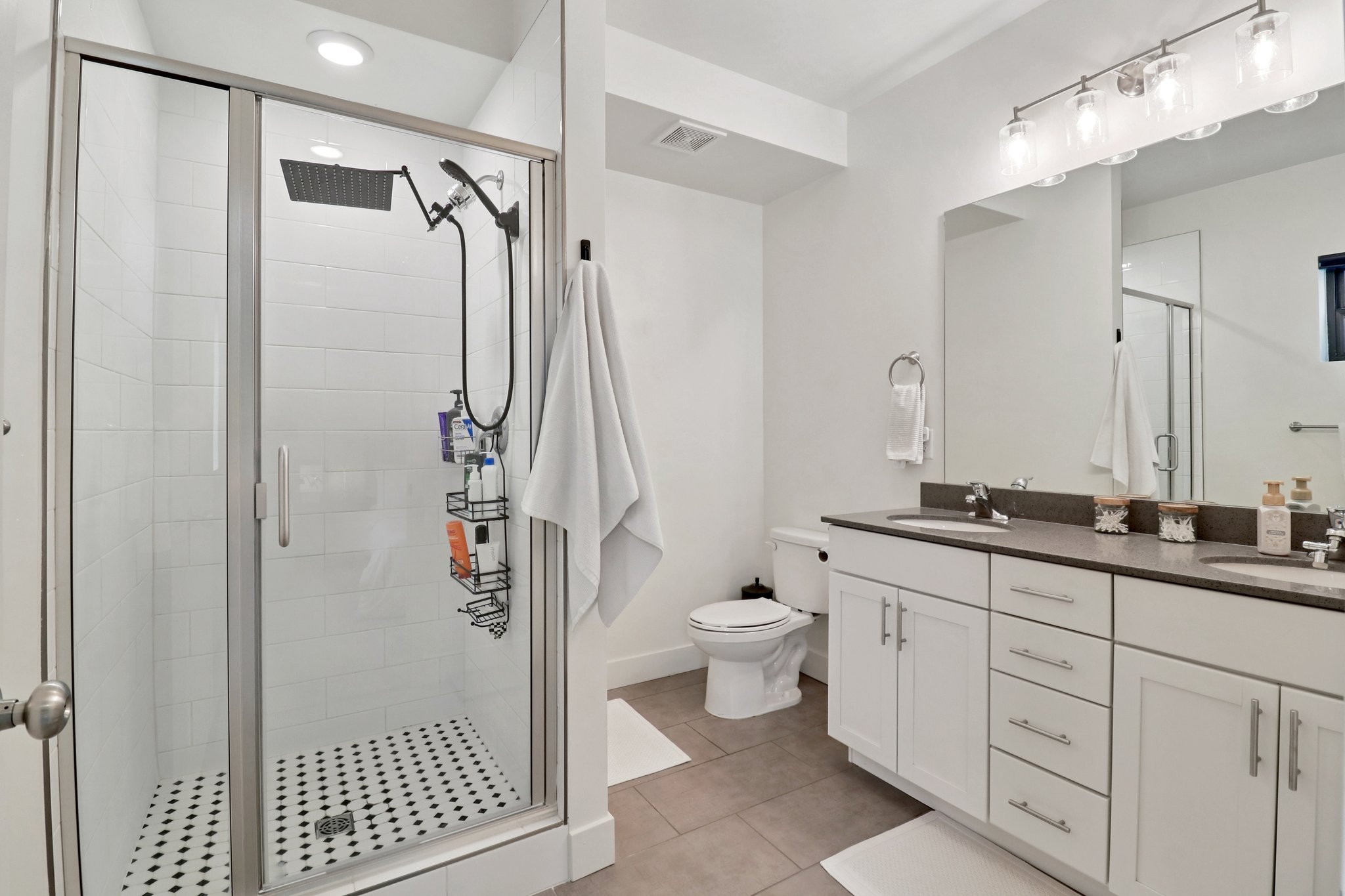 Bathroom with double vanity, a stall shower, and light tile patterned floors