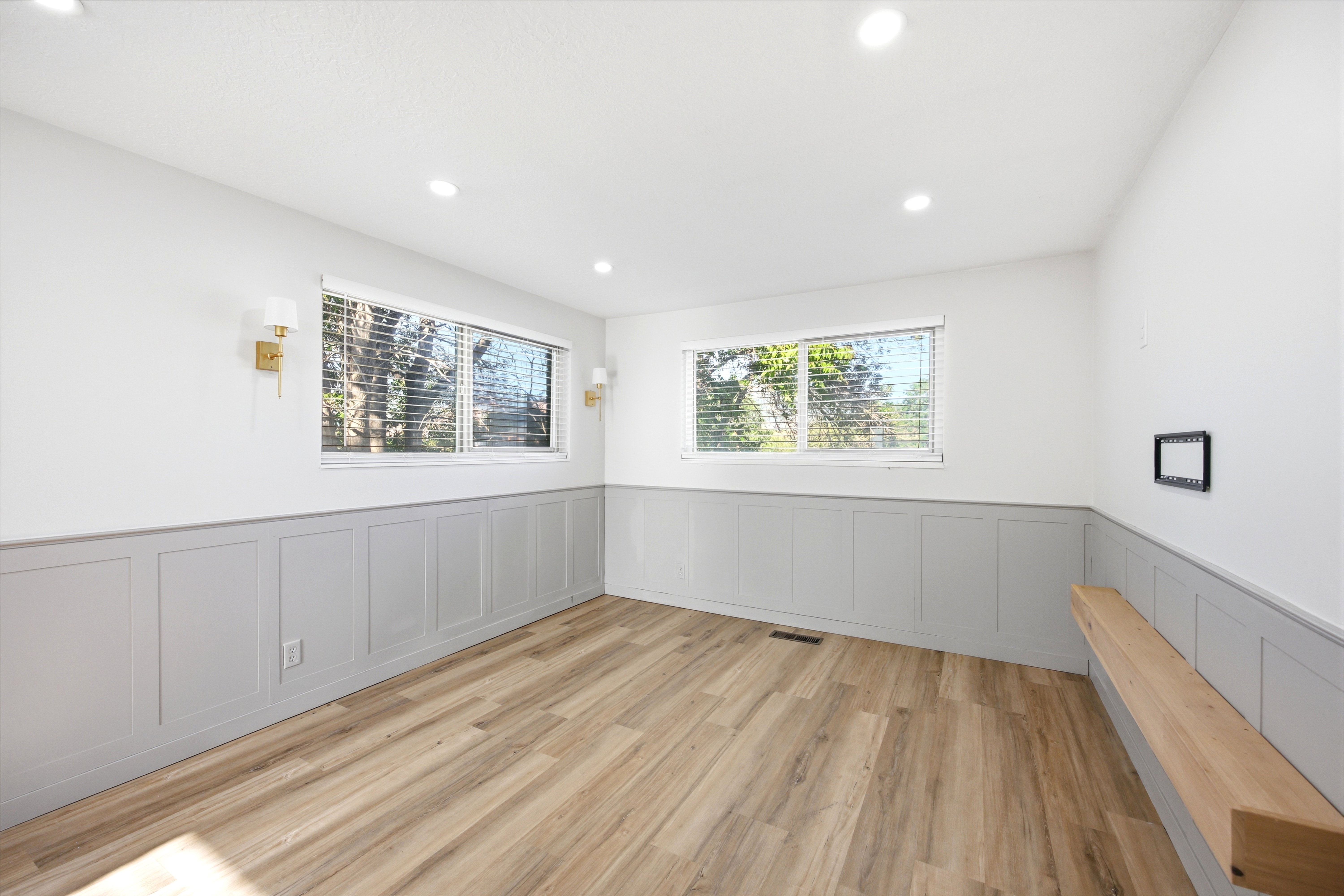 Room featuring light wood-finish flooring, two windows with blinds, recessed ceiling lighting, and a built-in wood bench