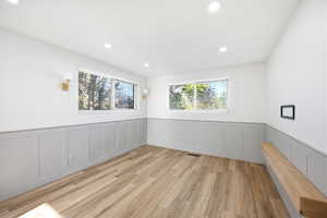 Room featuring light wood-finish flooring, two windows with blinds, recessed ceiling lighting, and a built-in wood bench