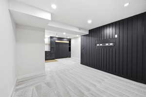 Contemporary living area featuring patterned carpet, recessed lighting, and a striking black accent wall with vertical paneling