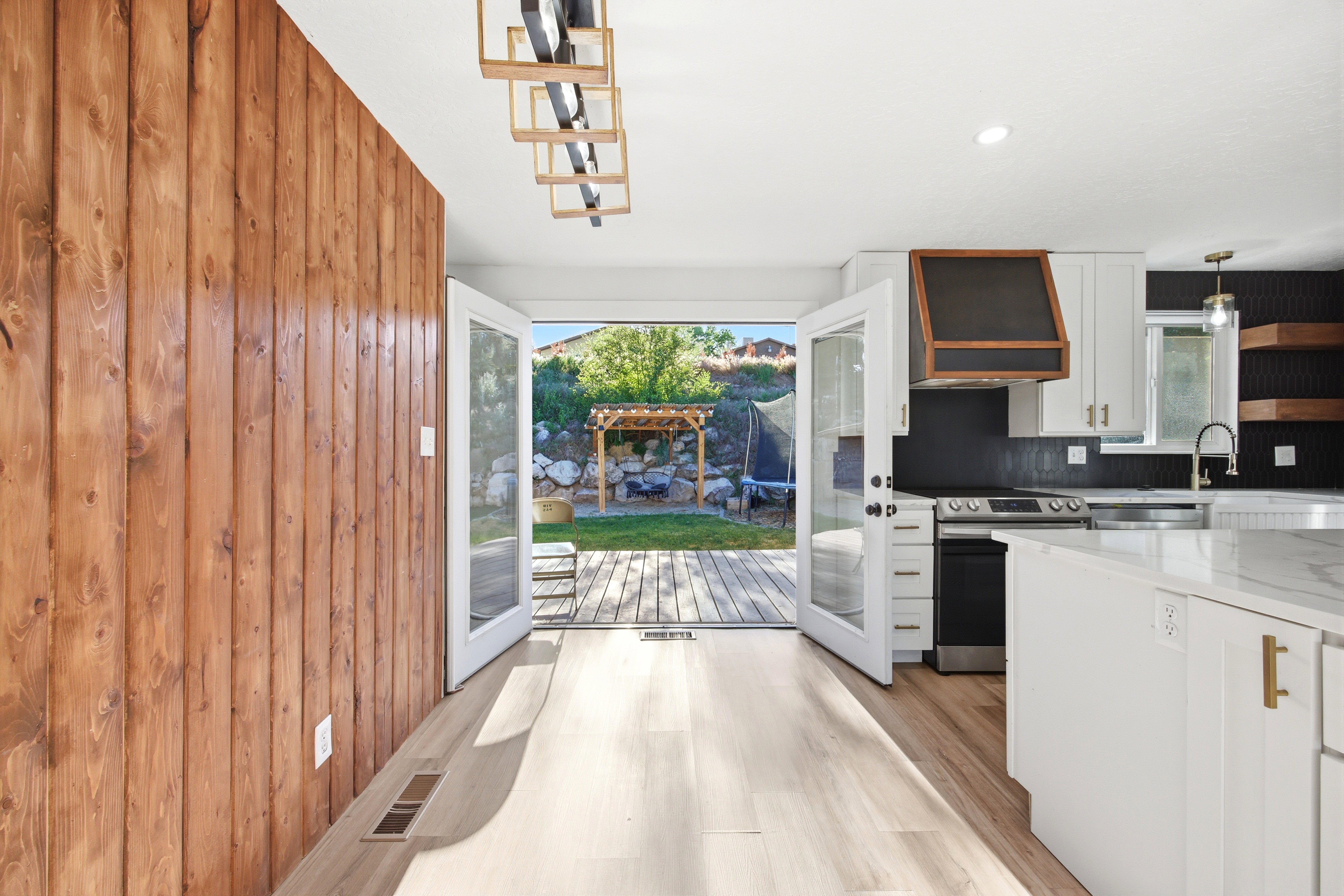 Kitchen featuring white cabinetry, a large island with a light-toned countertop, and a dark tile backsplash