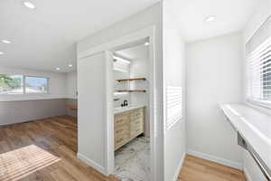Contemporary vanity space featuring a light wood-finish vanity with drawer storage, a black faucet, and a vessel sink