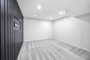 Recessed lighting illuminates a spacious room featuring a distinctive black paneled accent wall