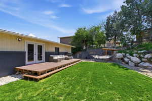 View of green lawn featuring french doors, an outdoor living space, and a deck
