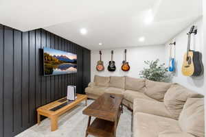 Living room with wooden walls, carpet flooring, and recessed lighting