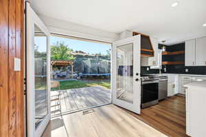 Kitchen featuring wood-finish flooring, white cabinetry, and stainless steel appliances
