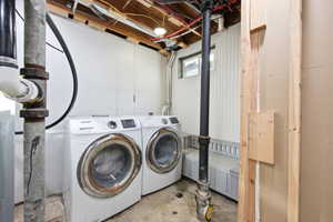 Dedicated laundry area featuring a washer and dryer, exposed ceiling joists, and white beadboard paneling